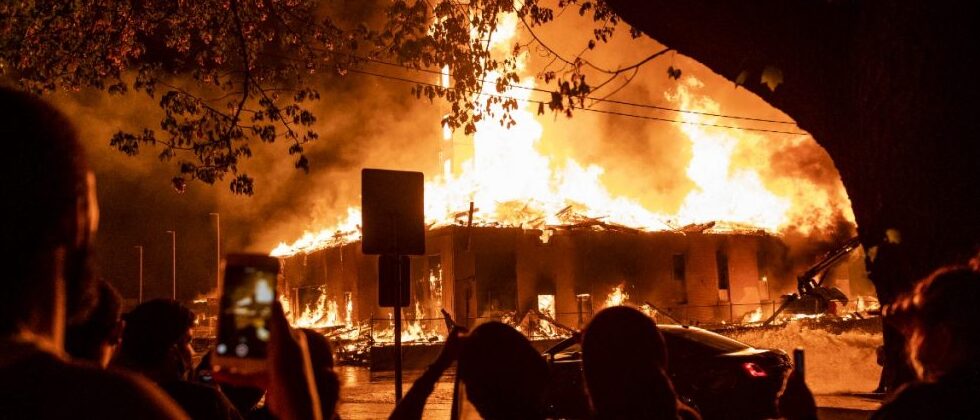 manifestantes em frente &agrave; uma delegacia em chamas
