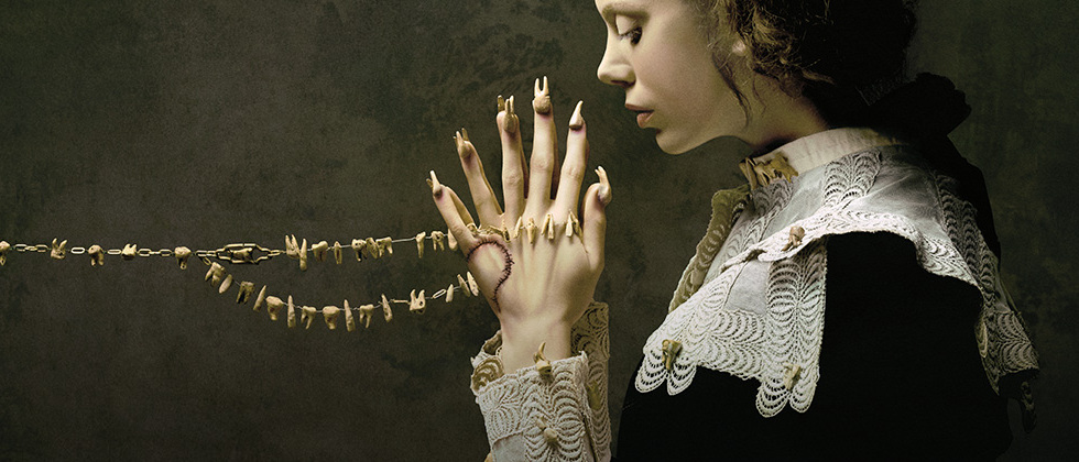 mulher com olhando para as duas m&atilde;os como se estivesse rezando