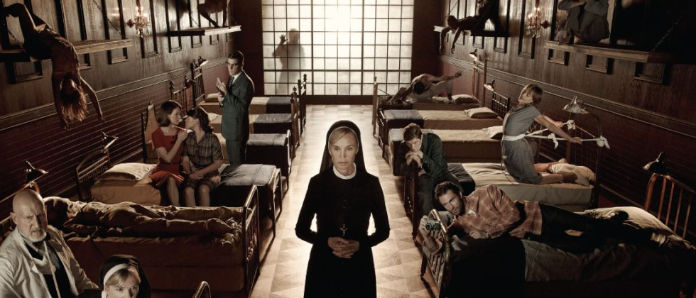 pessoas deitadas em macas e uma freia no meio em american horror story asylum