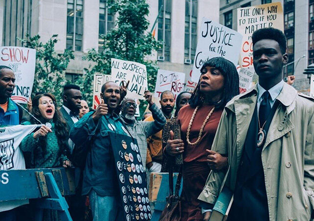 dois personagens de olhos que condenam passando em meio a um protesto