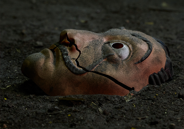 Máscara no chão quebrada ao meio, bem suja também. Imagem utilizada como o cartaz de anúncio da 5ª e última parte de La Casa de Papel